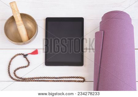 Rolled Yoga Mat, Wooden Mala Beads, Tibetan Bowl And Tablet On Wooden Background. Online Yoga And Me