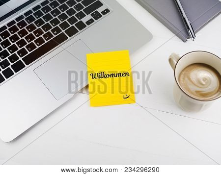 Willkommen Or Welcome With Smiley Face Icon On Desk