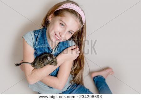 Smiling little girl holding a degu on her arms