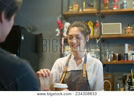 Happy Woman Or Waiter Giving Bag And Paper Cups With Hot Drinks To Customer At Coffee Shop. Takeaway