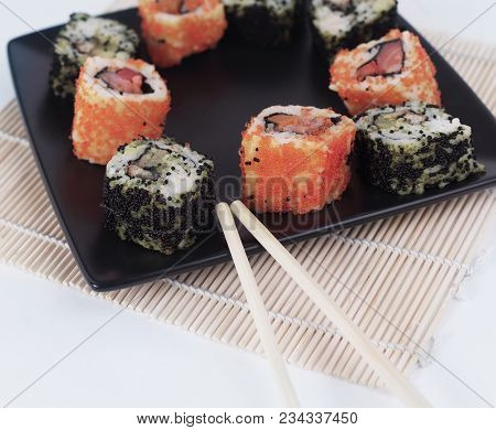 Different Types Of Maki Sushi On A Black Plate.isolated On White Background