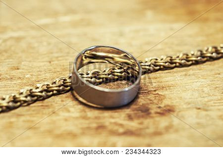 Silver Bracelet With Gold Snap Hook C With Diamonds, Rings With Stones Lie On A Textured Tree.
