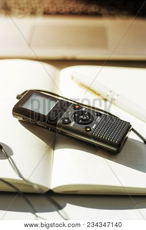 Dictaphone With Headphones On A Light Worktable Of A Journalist With A Notebook, A Green Succulent A