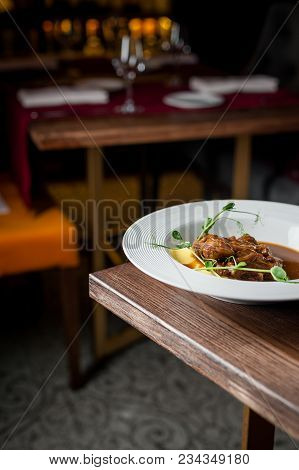 The Main Meat Dish On A Large Deep Plate. Restaurant. Gray Background, Dark Background, Parquet In T