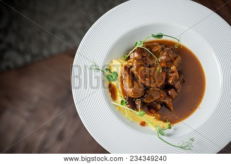 The Main Meat Dish On A Large Deep Plate. Restaurant. Gray Background, Dark Background, Parquet In T