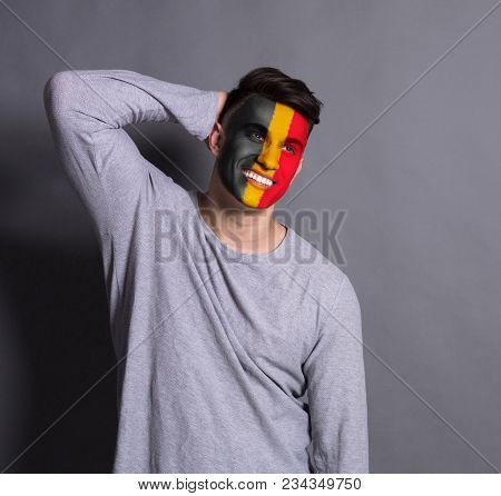 Portrait Of Man With The Flag Of Belgium Painted On His Face. Football Or Soccer Team Fan, Sport Eve