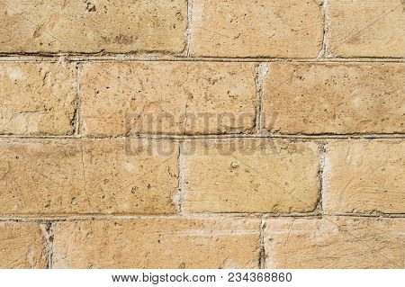 Close-up Textured Background Of A Stone Brick Of Yellow Antediluvian Masonry. Partially Destroyed Wa