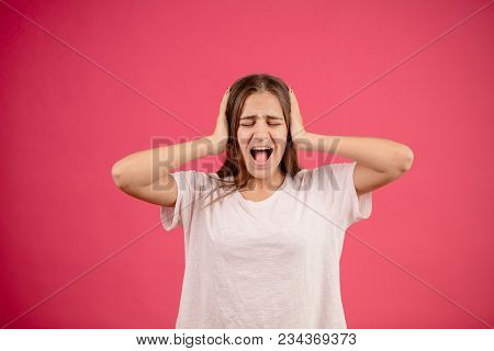 Young Annoyed Female With Open Mouth And Closed Eyes Is Closing Her Ears With Hands Because Of Loud 