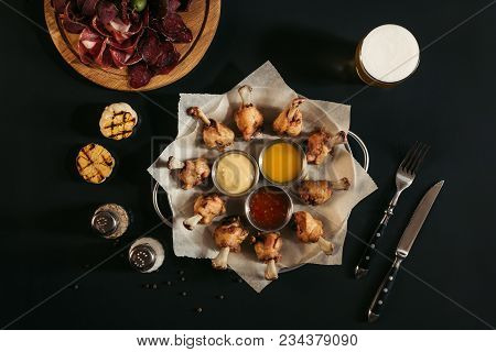 Fried Chicken With Sauces, Spices, Glass Of Beer And Gourmet Assorted Craft Meat On Black