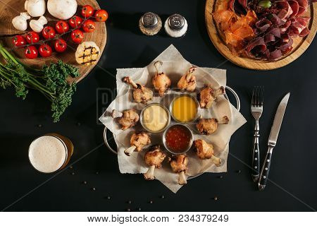 Top View Of Delicious Roasted Chicken With Various Sauces, Assorted Meat And Vegetables On Black