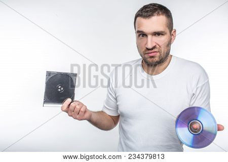 Clueless Man Holding A Compact Disk And Staring At Camera, Obsolete Technology Concept
