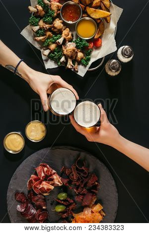 Partial Top View Of People Drinking Beer And Eating Assorted Meat And Baked Potatoes With Roasted Ch