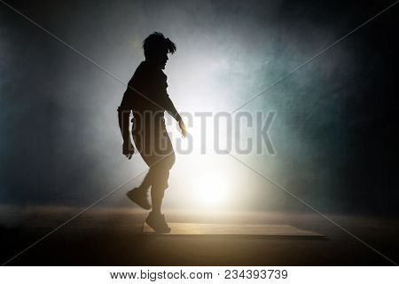 Figure Of Sporty Dancer Who Beginning To Do Stunt Of Break Dance On The Black Background. Preparatio