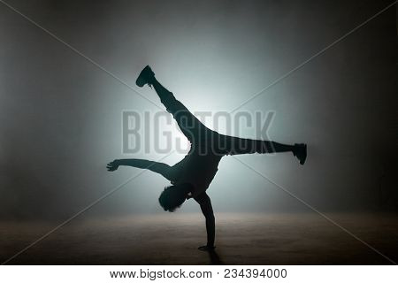 Silhouette Of B-boy Performing Flares On The Light Street, Difficult Stunt. Balance Oneself. Maintai