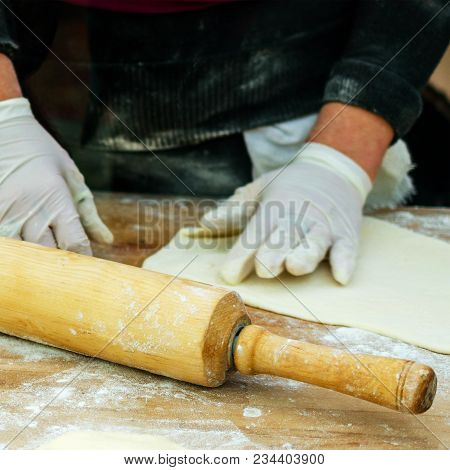 Preparing Food. Human Hands In Gloves Make Dough Products. Rolling Pin  For The Dough Next To It. Sq