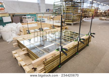 production, manufacture and industry concept - mirror panels loaded on palette and fastened by bar clamps at furniture factory workshop