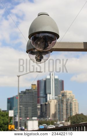 Dome Security Camera On Blue Sky Background Of Skyscrapers In City