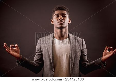 Fashion African Businessman Is Doing Yoga With Closed Eyes. Hobby. Relaxing At Work. Inspiration. Ta