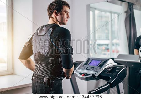 Ems Training. Fit Man Wearing Black Electromiostimulation Suit Preparing For Running On Treadmill Ne