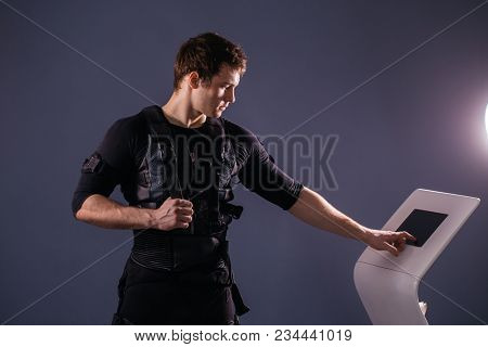 Male Athlete Regulating Intensity Of Ems Electro Muscular Stimulation Machine