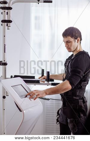 Male Athlete Pushing On Screen On Ems Machine Regulating Intensity