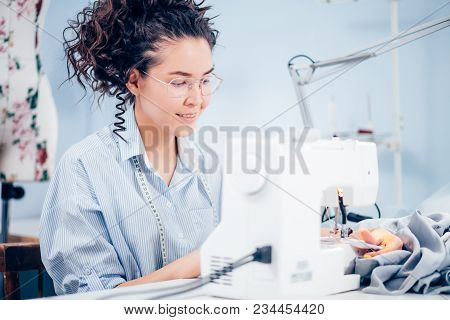 Beautiful Seamstess Is Sitting In Front Of Motion Blur Sewing Machine At Work. Perfect Designer. Sta