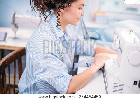 Cropped Photo Of Young Tailor Making Clothers For Customers On Sewing Machine At Design Studio. Full