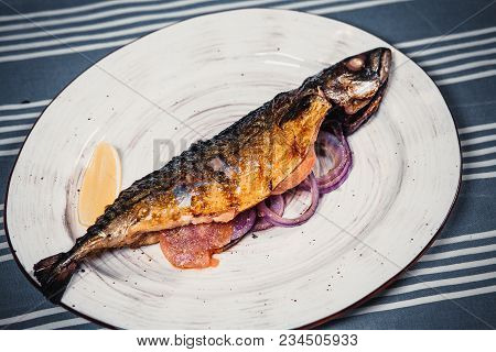 Fried Fish Served With Lemon Slices, Lettuce, Tomatoes, Rosemary And Onion Rings Lying On Plate, Who