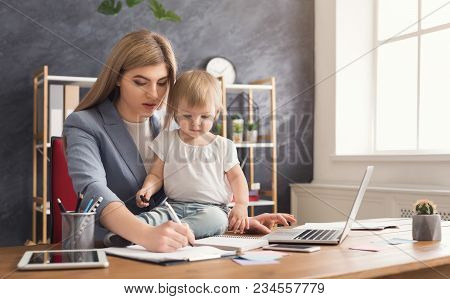 Beautiful Business Mom Working On Laptop And Taking Notes While Spending Time With Her Cute Baby. Bu