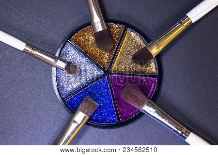 A Palette Of Colorful Glitter Eyeshadow And Profeccional Make Up Brushes On A Black Background, Clos