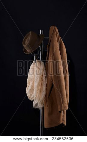 Classic Coat, Hat And Scarf Hanging On Coat Rack Isolated On Black