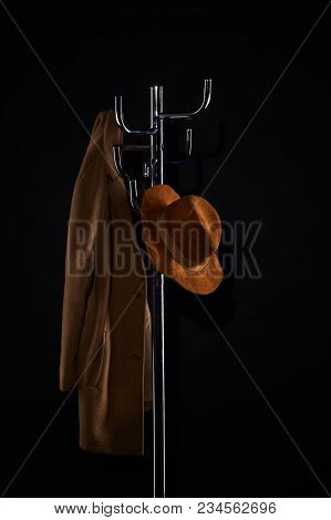 Hat And Coat Hanging On Coat Rack Isolated On Black