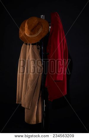 Coats And Hat Hanging On Coat Rack Isolated On Black