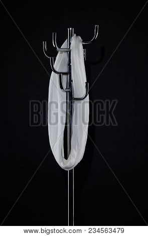 White Scarf Hanging On Coat Rack Isolated On Black