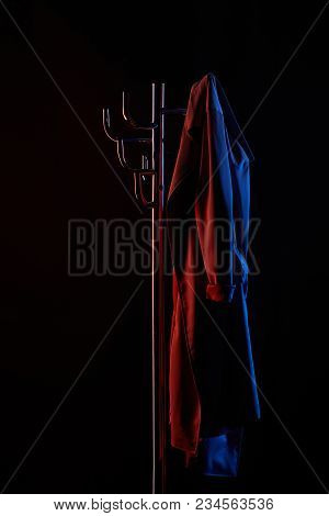 Coat Hanging On Coat Rack Under Toned Light Isolated On Black