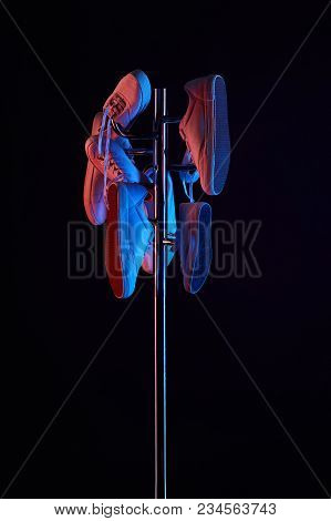 Various Shoes Hanging On Coat Rack Under Toned Light Isolated On Black