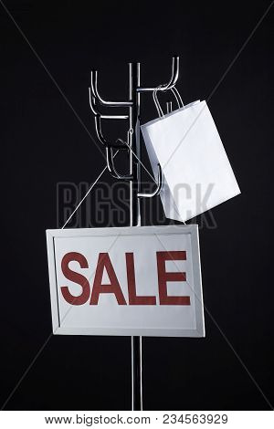 Sale Signboard And Paper Bag On Coat Rack Isolated On Black