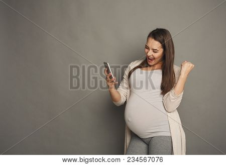 Surprised Pregnant Woman Using Smartphone Copy Space. Excited Expectant Lady With Open Mouth Looking