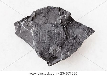 Macro Shooting Of Natural Mineral Rock Specimen - Raw Shungite Shale Stone On White Marble Backgroun