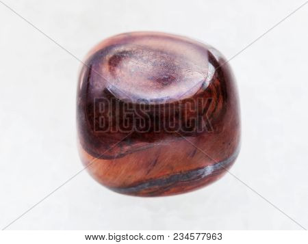 Macro Shooting Of Natural Mineral Rock Specimen - Tumbled Jaspilite Gem Stone On White Marble Backgr