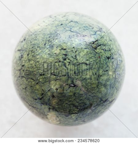 Macro Shooting Of Natural Mineral Rock Specimen - Bead From Serpentine Gemstone On White Marble Back