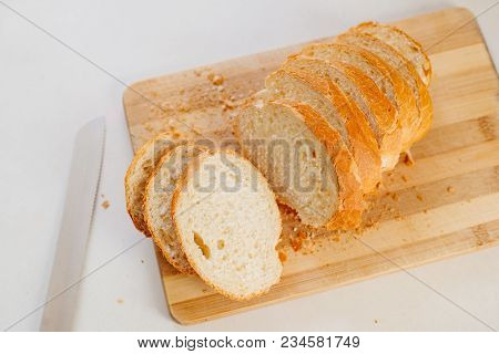 A Fresh Loaf Cut Into Pieces Lies On A Wooden Board, Next To A Knife-file For Bread. The Crust Crumb
