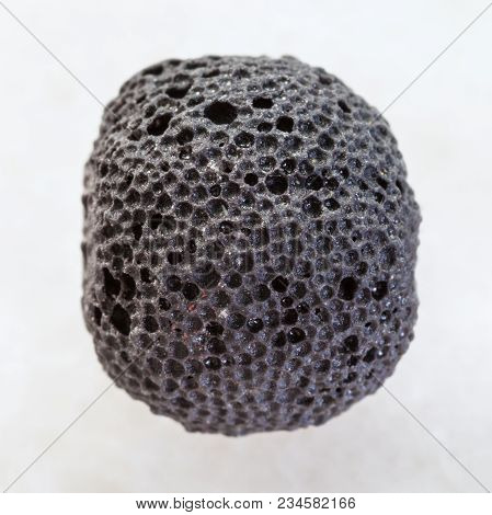 Macro Shooting Of Natural Mineral Rock Specimen - Black Pumice Bead On White Marble Background From 