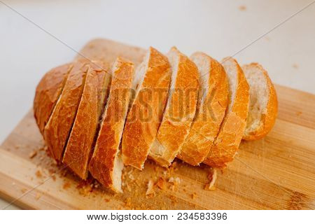 A Fresh Loaf Cut Into Pieces Lies On A Wooden Board, Next To A Knife-file For Bread. The Crust Crumb
