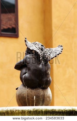 Cupid Child With A Wing Sitting On The Ball Behind.