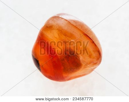 Macro Shooting Of Natural Mineral Rock Specimen - Tumbled Carnelian Gem Stone On White Marble Backgr