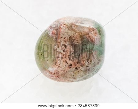 Macro Shooting Of Natural Mineral Rock Specimen - Tumbled Moss Agate Gemstone On White Marble Backgr