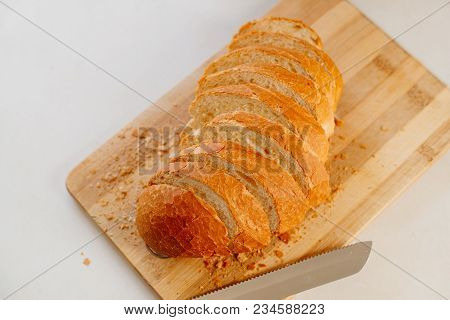 A Fresh Loaf Cut Into Pieces Lies On A Wooden Board, Next To A Knife-file For Bread. The Crust Crumb