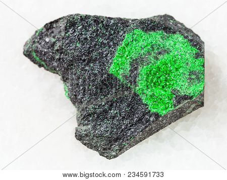 Macro Shooting Of Natural Mineral Stone Specimen - Uvarovite Crystals On Raw Rock On White Marble Ba