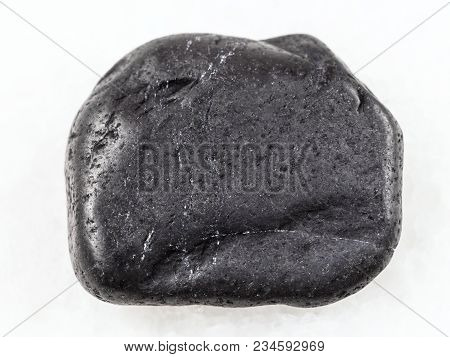 Macro Shooting Of Natural Mineral Rock Specimen - Pebble Of Shungite Gemstone On White Marble Backgr